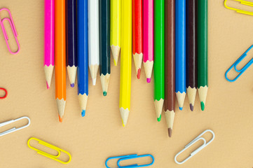 Lots of colorful pencils and paper clips on a nice beige background