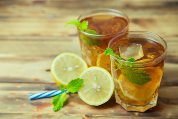 Iced tea with lemon slices and mint on wood background