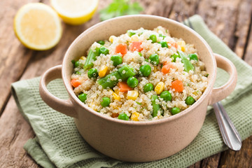 Fresh homemade cooked white quinoa with colorful vegetables (green peas, sweet corn kernels, green beans, carrots) and parsley in bowl (Selective Focus, Focus one third into the dish)
