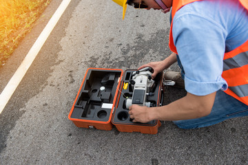 Civil engineer with Surveyor equipment tacheometer or theodolite outdoors at construction site on the road.