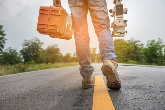 Civil engineer with Surveyor equipment tacheometer or theodolite outdoors at construction site on the road.