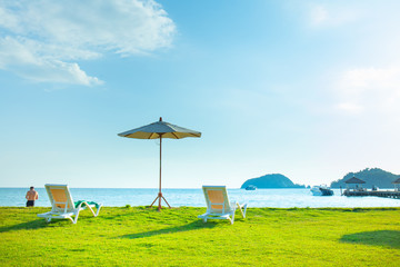 Beach chairs and beach umbrellas are on the lawn at the beach.Sea view and bright sky.