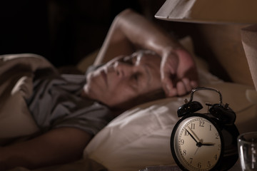 Depressed senior man lying in bed cannot sleep from insomnia