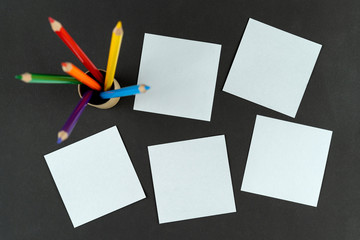 notes lie on black table, and multi colored lgbt pencils stand in place in unfocus. Mock up, copy...