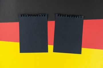 Blacklist Germany. Mourning, ban, sanctions, politics. black sheet of notebook lies on German flag. Mock up, copy space, pattern, cardboard texture.