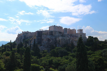 Fototapeta na wymiar Fantastic panoramic aerial view to ancient greek landmark acropolis of athens situated on the hill and surrounded by green trees under blue sky with clouds