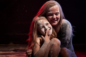 Two sisters in black studo with red and blue light during photoshoot with flour