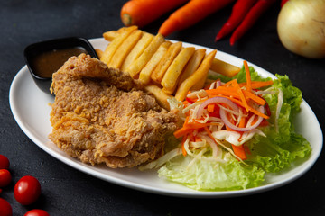 Fried chicken with french fries on dark background