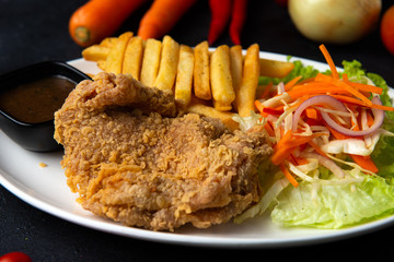 Fried chicken with french fries on dark background