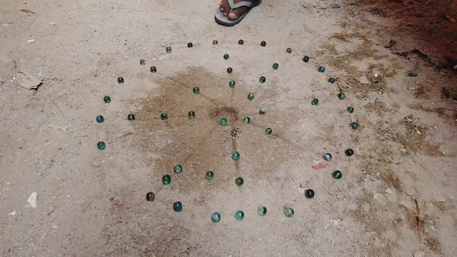 Kanche is a popular game in rural Southeast Asia and India, played with round glass marbles and aim is to collect as many as possible by shooting and striking other marbles. 4k 60fps handheld close-up