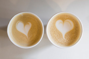 Two coffee cups with heart shape latte art on white table. Love, Valentine's Day concept. Top view, flat lay, copy space