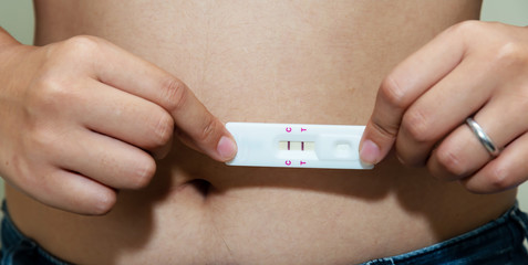 Woman holding pregnancy test in hands, looking at result, gynecology close-up