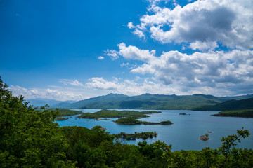 Fototapeta na wymiar Montenegro, Mountains covered by green trees and forest surrounding seascape of lake slano peninsulas near niksic city from above
