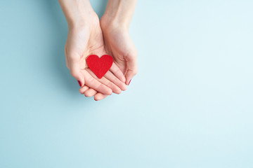 a person holding red heart in hands, donate and family insurance concept, on aquamarine background, copy space top view - obrazy, fototapety, plakaty