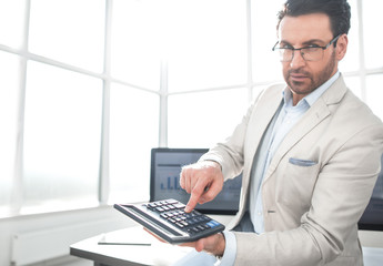 Fototapeta na wymiar confident businessman pointing to calculator