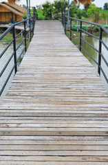 Fototapeta premium Wooden bridge crossing river to countryside pavilion in Thailand.
