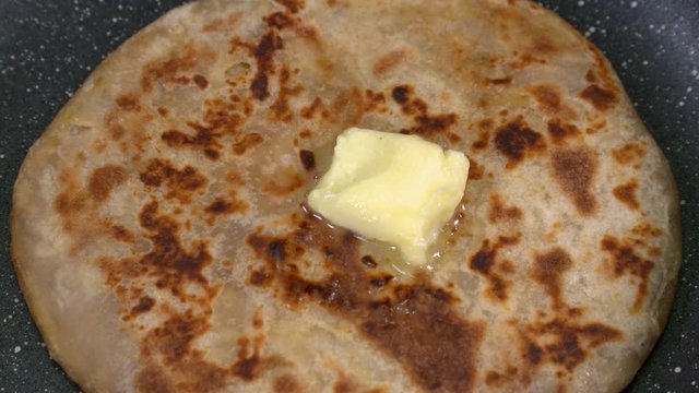 Closeup shot of butter melting on a stuffed parantha. 