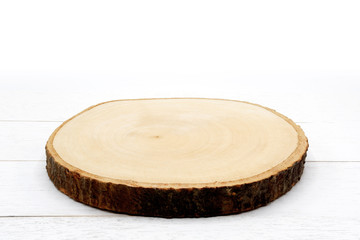 Empty rustic wooden slice serving board on white wooden table.