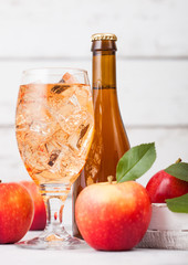 Bottle and glass of homemade organic apple cider with fresh apples in box on wooden background