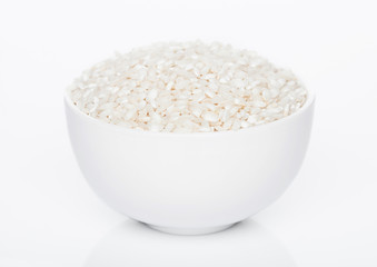 White bowl of raw organic arborio risotto rice on white background. Healthy food.