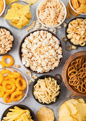 All classic potato snacks with peanuts, popcorn and onion rings and salted pretzels in bowl plates...