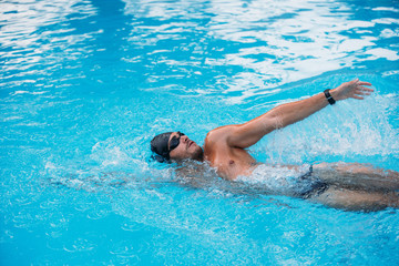 Athletic Young man swimming on Backstroke style. Swimming competition.