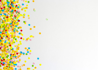 Confetti scattered in different colors on the white background. Festive confetti. The decor for the party.