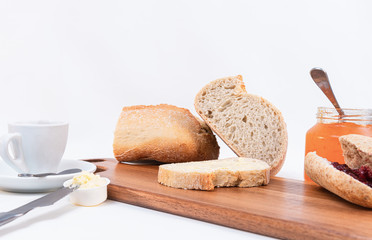 cereal bread slices with butter and jar with homemade jam closeup on rustic wooden table. White background.