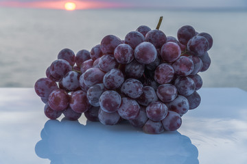Tasty and sweet bunch of freshly harvested purple grapes on a white table