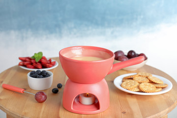Ceramic pot with white chocolate fondue on table