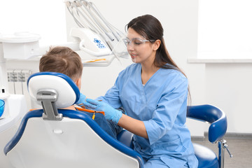 Professional dentist working with little boy in clinic