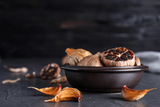 Bowl with aged black garlic on table. Space for text