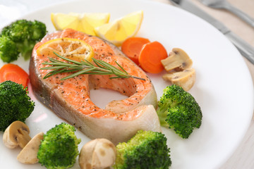 Plate with salmon steak and garnish prepared in multi cooker on table, closeup