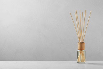Reed air freshener on table against grey background, space for text