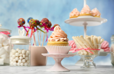 Candy bar with different sweets on white marble table against color background