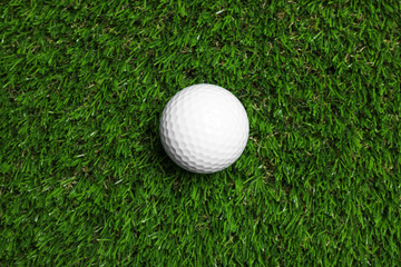 Golf ball on green artificial grass, top view