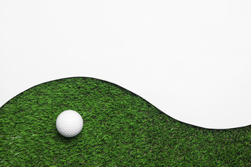 Golf ball and white paper on green artificial grass, top view with space for text
