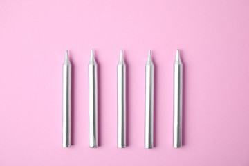 Silver birthday candles on pink background, top view