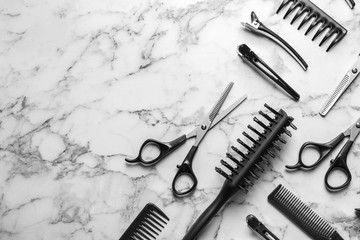 Flat lay composition with scissors and other hairdresser's accessories on white marble background....