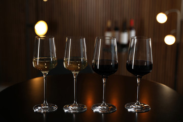 Glasses of different wines on table against blurred background