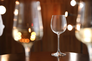 Empty wine glass on table against blurred background. Space for text
