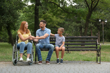 Fototapeta na wymiar Woman in wheelchair with her family at park