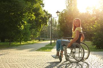 Happy woman in wheelchair at park on sunny day. Space for text