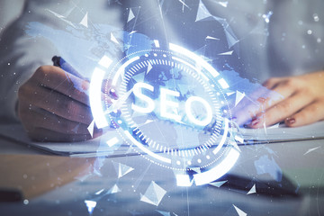 Double exposure of woman's hands making notes with SEO icon. Concept of Search engine optimization