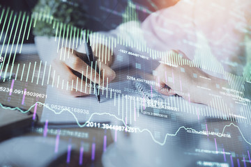 Financial forex graph displayed on hands taking notes background. Concept of research. Double exposure