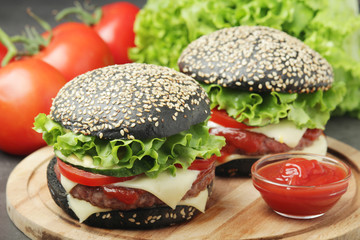 Two black burgers with vegetables and beef meat