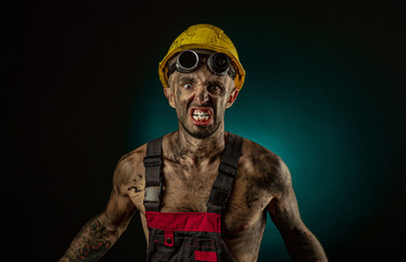 Portrait of happy smiling coal miner with his arms crossed against a dark background