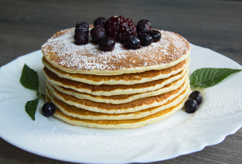 Pancake with powdered sugar, blueberries and blackberries on a plate