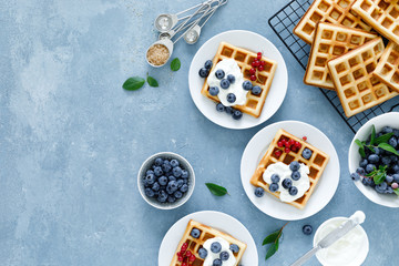 Traditional belgian waffles with cream cheese and fresh blueberry on blue background, top view
