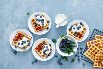 Obraz na płótnie Canvas Traditional belgian waffles with cream cheese and fresh blueberry on blue background, top view